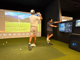Golfer completing a swing while an instructor reviews the shot at Clubhouse Hawaii