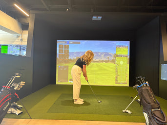 Beginner golfer preparing to hit in an indoor simulator bay