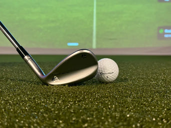 Golf wedge and ball on an indoor hitting mat